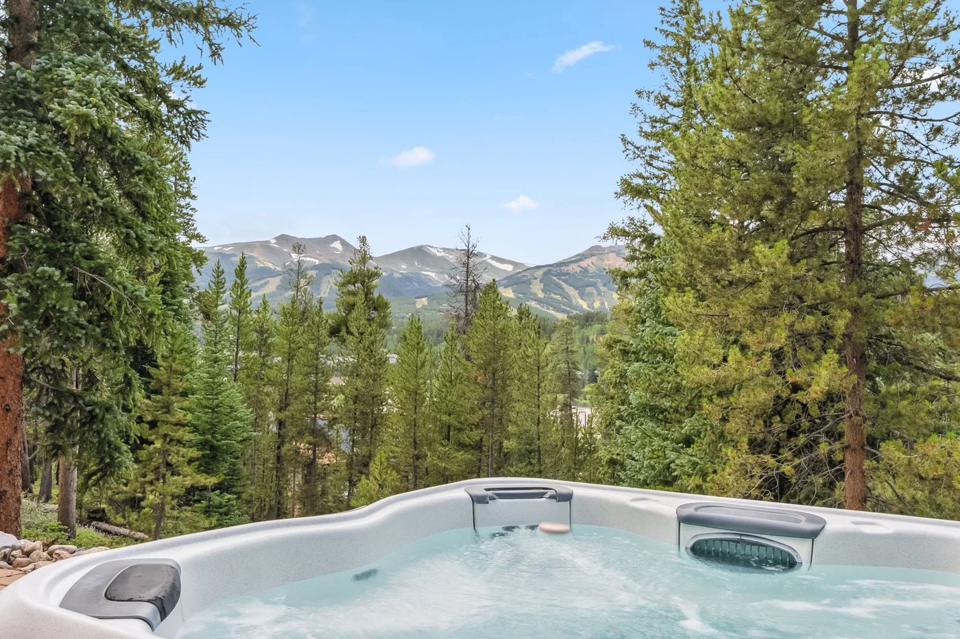 Una bañera de hidromasaje al aire libre ofrece vistas a un paisaje montañoso boscoso.
