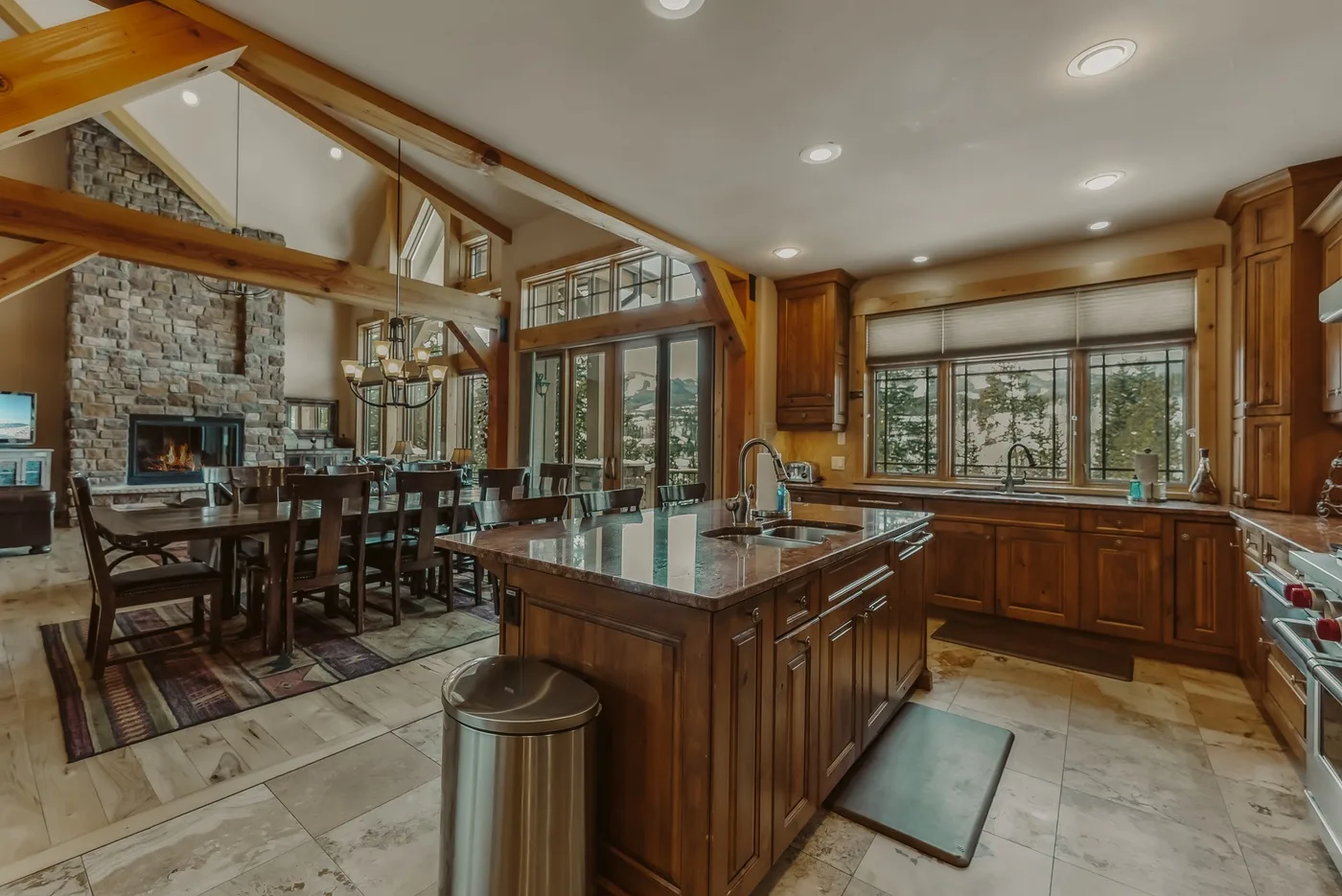Una cocina amplia con isla central y comedor junto a grandes ventanales.