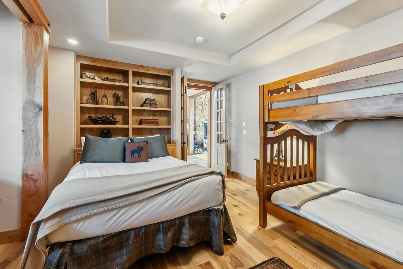 Un dormitorio con una cama doble, estanterías empotradas y una litera de madera.