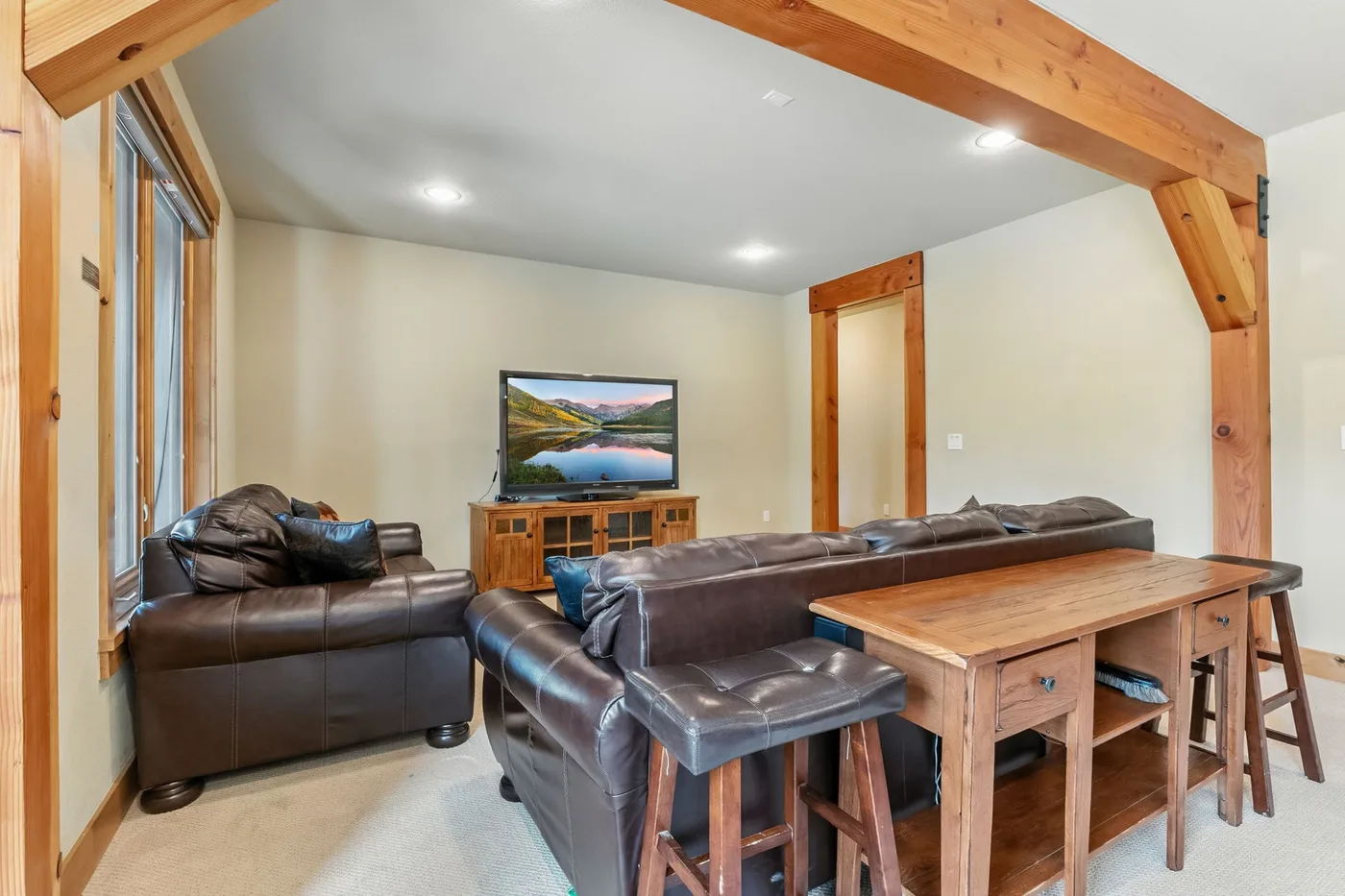 Una sala de estar con asientos de cuero, un televisor y una mesa de madera.