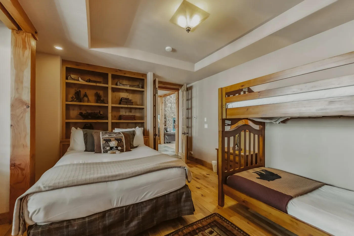 Un dormitorio con una cama grande, estanterías de madera y una litera.