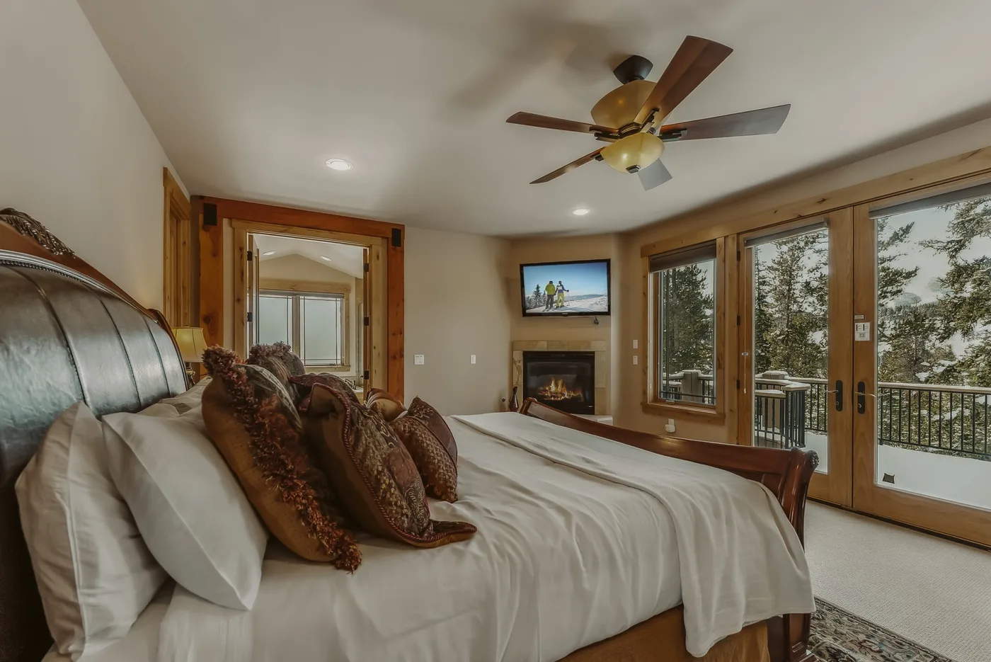 Un dormitorio con una cama grande y ventanas con vista a los árboles.