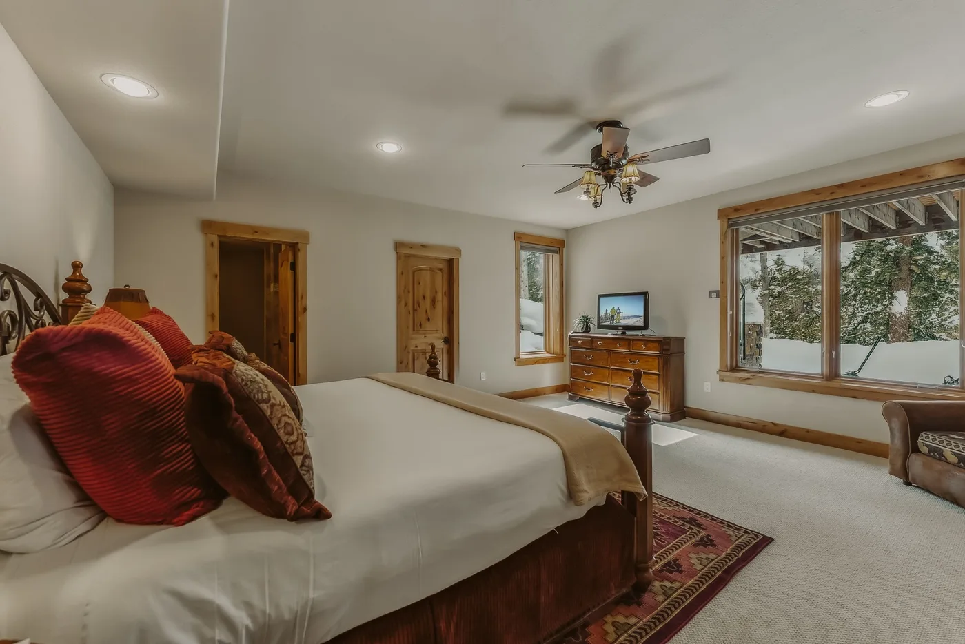 Un dormitorio con una cama, una cómoda de madera y una ventana grande.