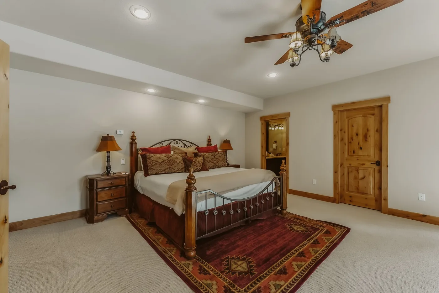 Un dormitorio con una cama grande, muebles de madera y una alfombra estampada.