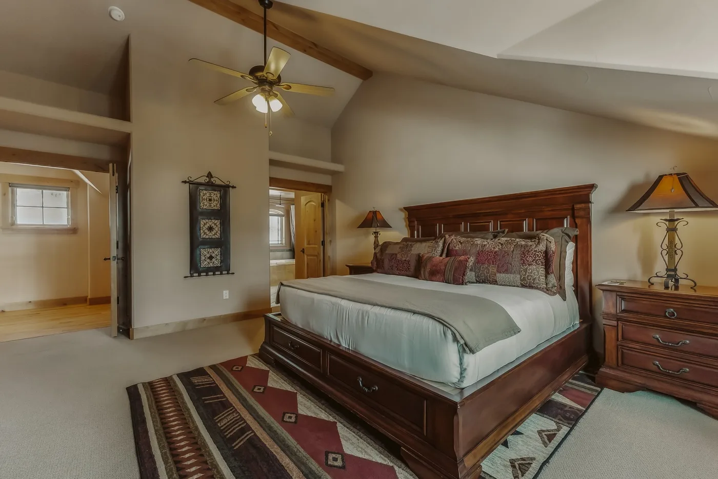 Un dormitorio con una cama de madera y alfombras estampadas.