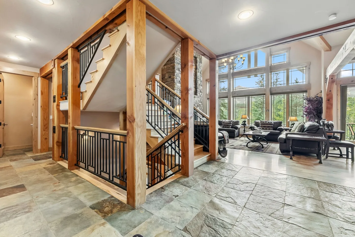 Una sala luminosa con grandes ventanas y una escalera de madera.