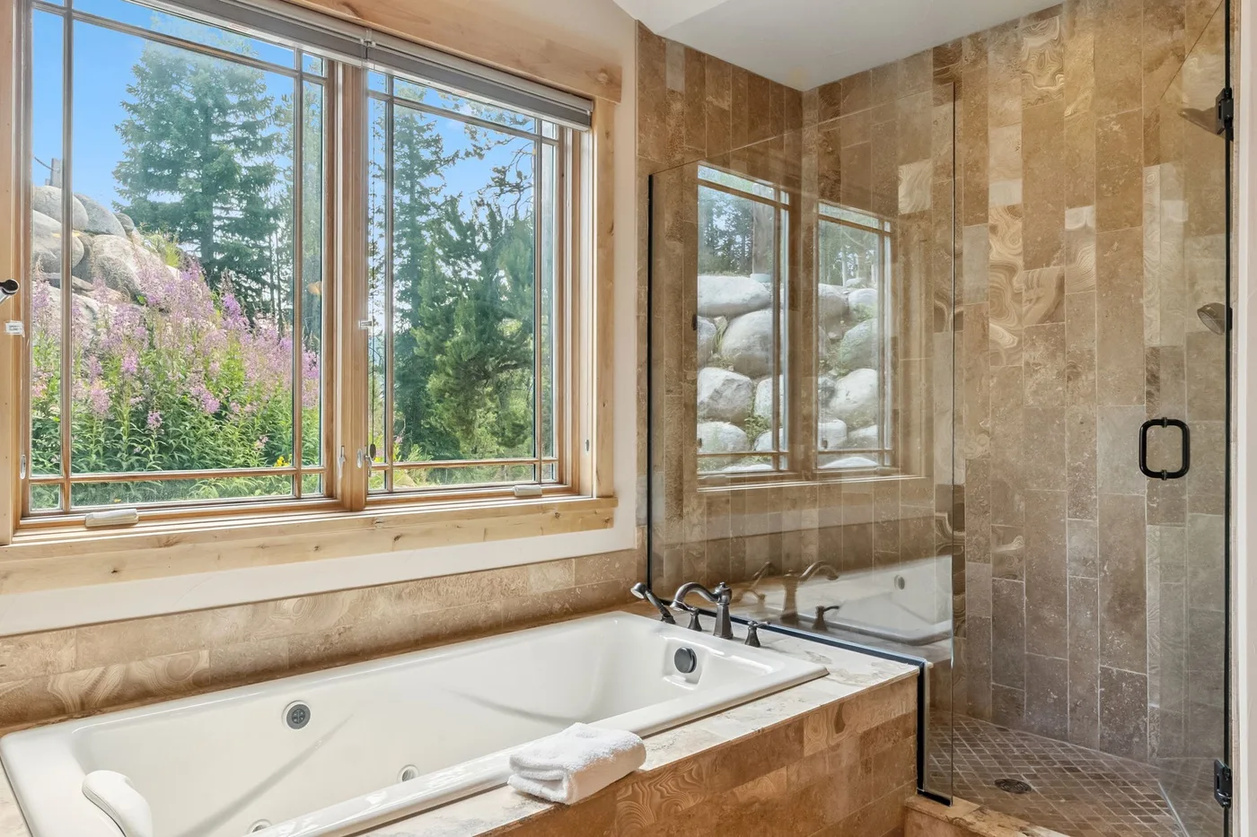 Baño con azulejos, bañera y ducha con mampara de vidrio.