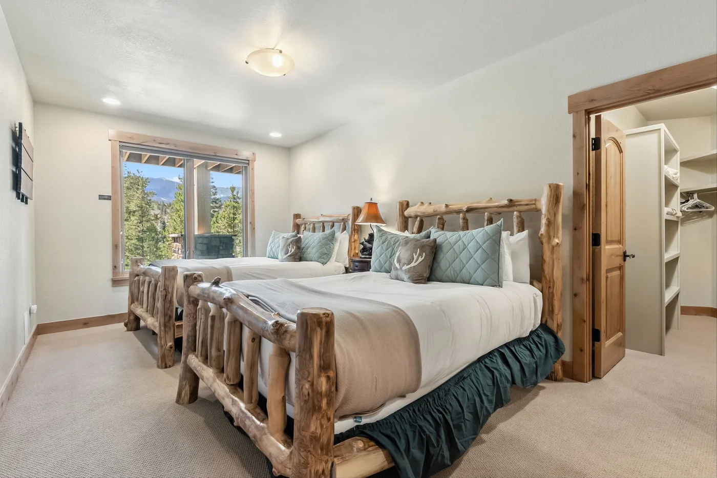 Un dormitorio con dos camas, estructuras de madera rústica y una ventana amplia.