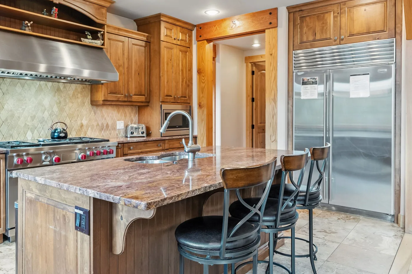 Cocina con gabinetes de madera, una isla grande y electrodomésticos de acero inoxidable.