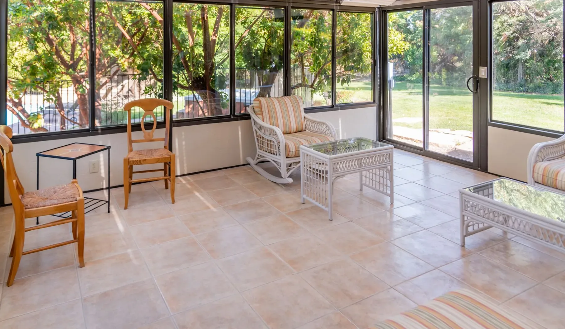 Un solárium con asientos y grandes ventanas con vistas a un jardín.