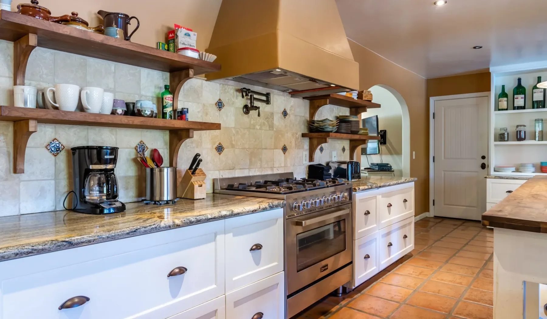 Una cocina con estufa, salpicadero de azulejos y gabinetes blancos.