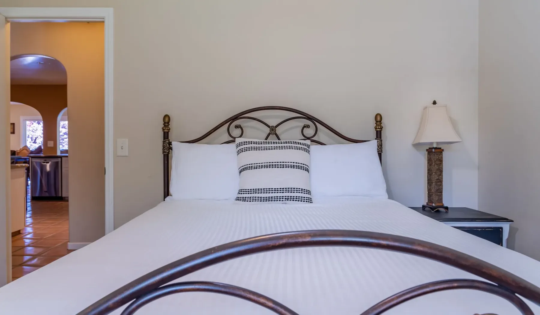 Un dormitorio con una cama bien tendida y una lámpara de noche.