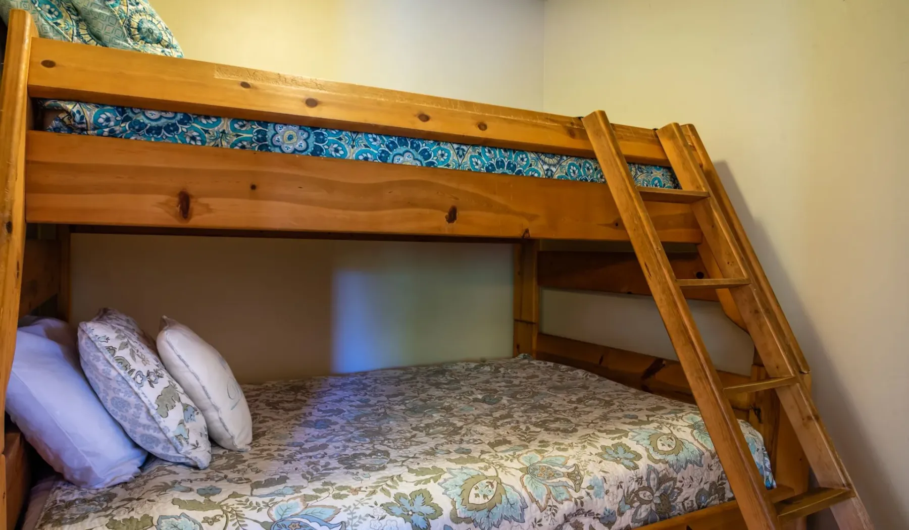 Un dormitorio con una litera de madera y ropa de cama floral.