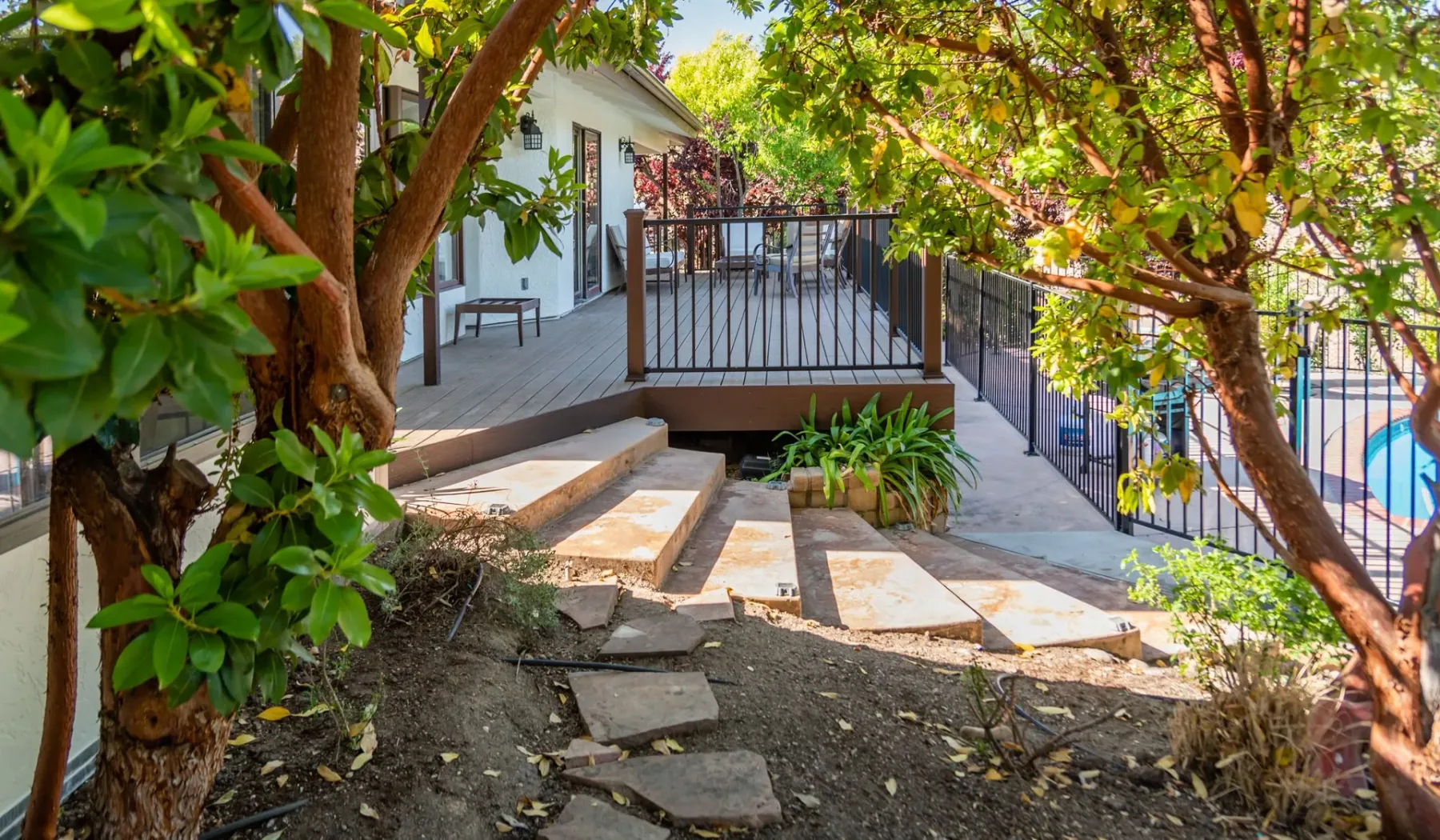 Un patio exterior frondoso con una terraza elevada y árboles alrededor.