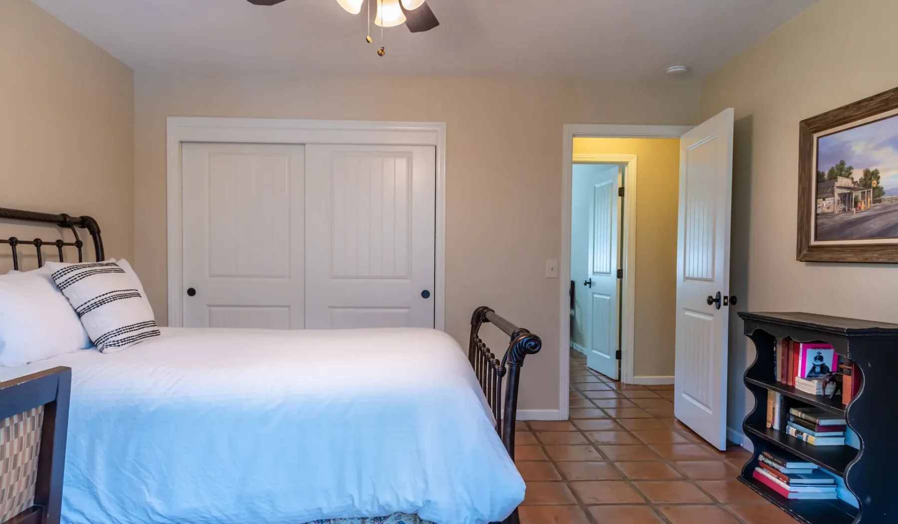 Un dormitorio con una cama, suelo de baldosas y una puerta abierta.