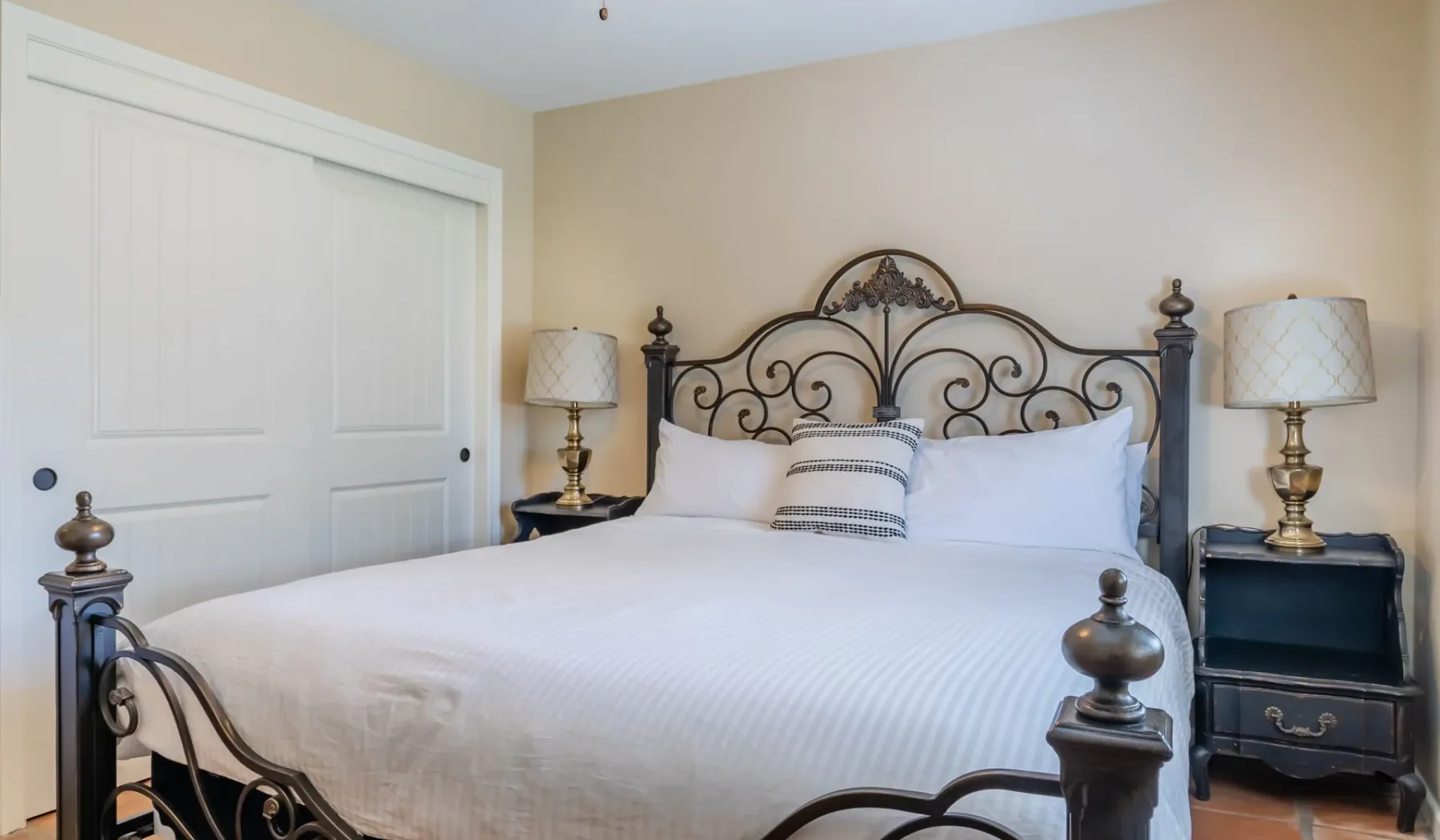 Un dormitorio con una cama blanca y un cabecero de metal ornamentado.