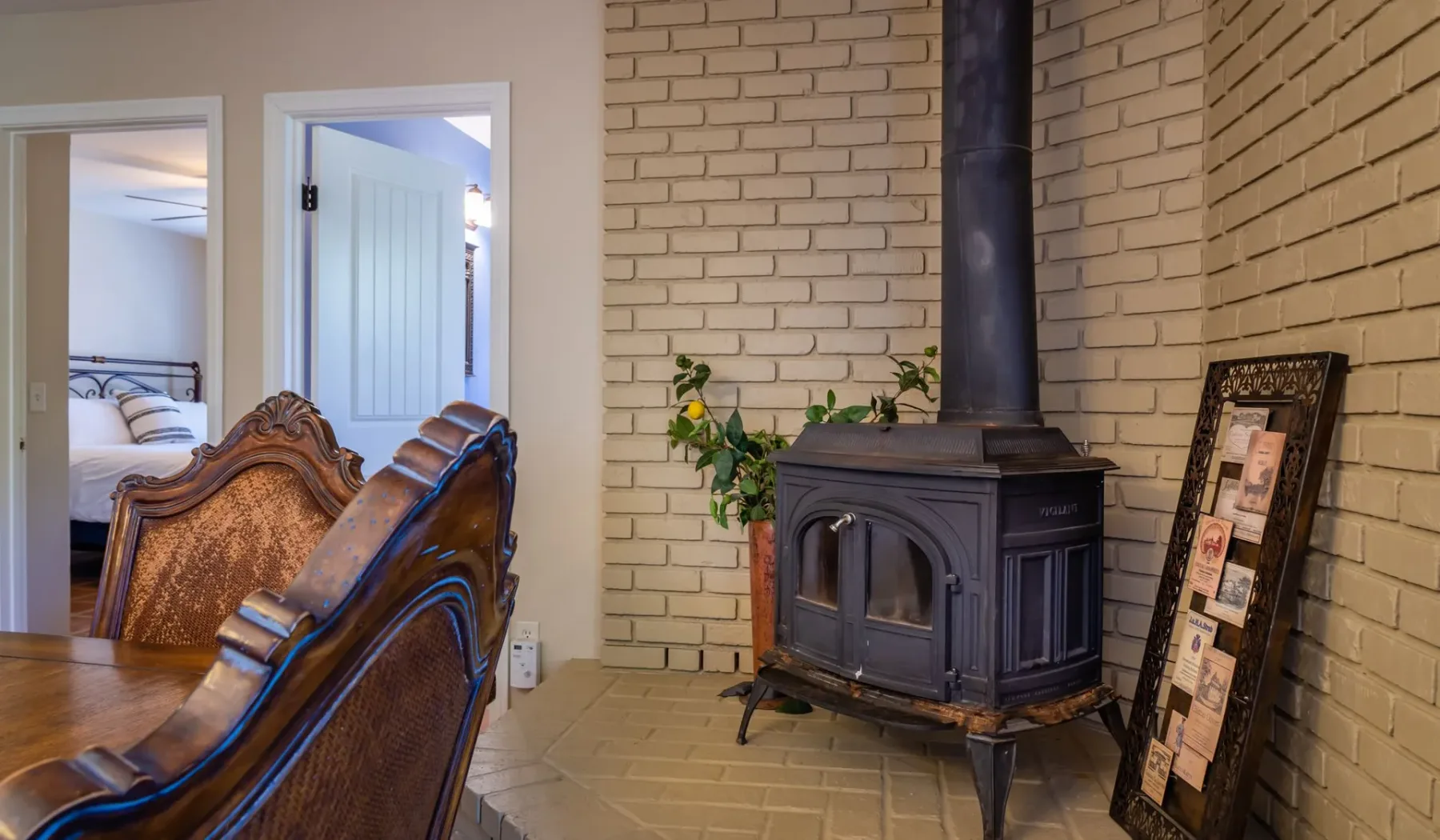 Una sala de estar con una estufa de leña junto a una pared de ladrillo y asientos de madera tallada.