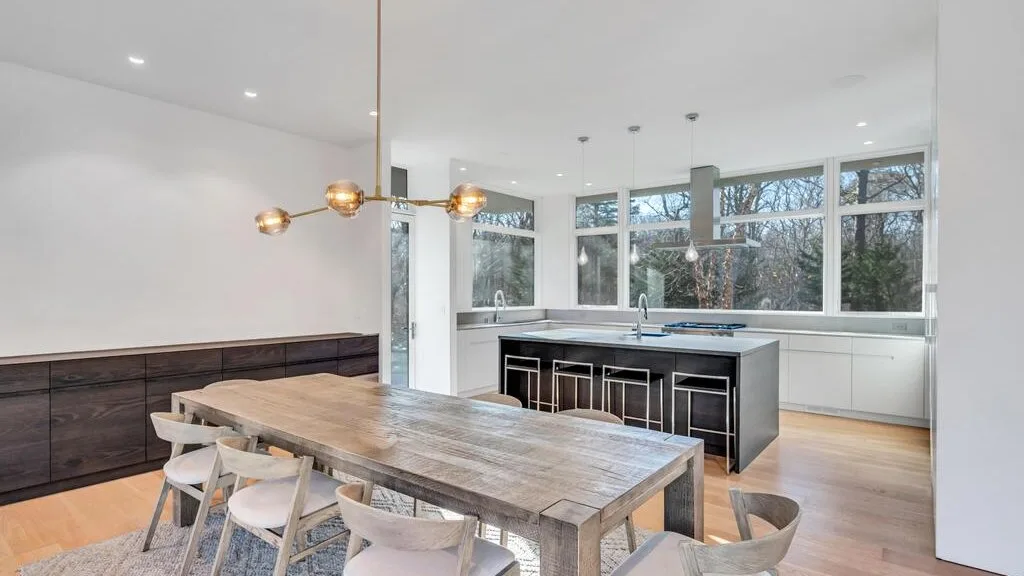 Una luminosa cocina abierta con comedor, una isla amplia y una mesa de madera.