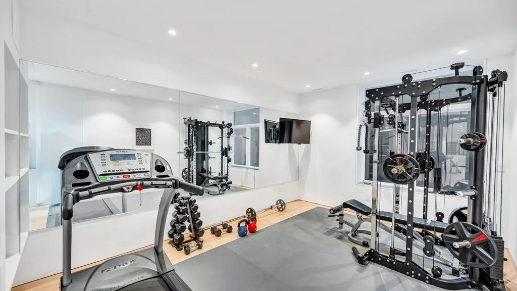 Un gimnasio interior luminoso con una cinta de correr, pesas y máquinas de ejercicio.