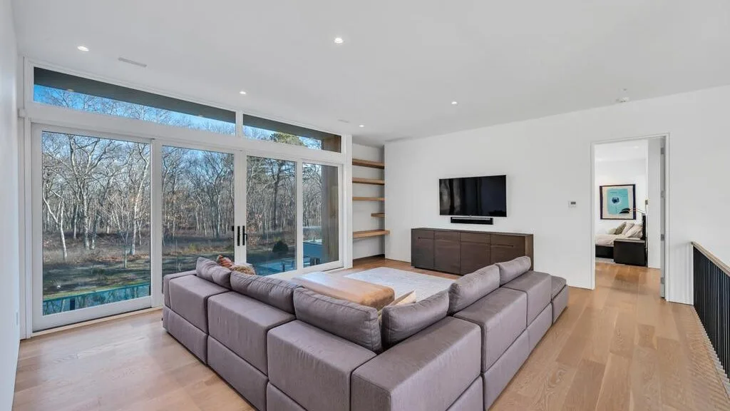 Una sala luminosa con asientos seccionales junto a grandes ventanas.