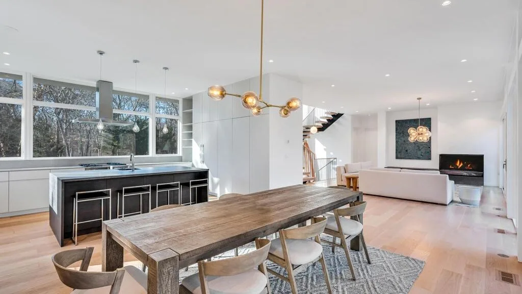 Una luminosa cocina-comedor de planta abierta con una mesa larga de madera e isla.