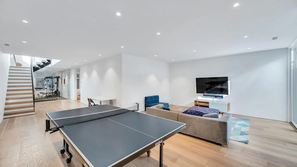Una luminosa sala de recreación cuenta con una mesa de ping-pong y una zona de estar con televisor.
