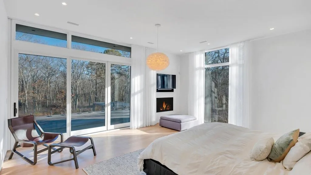 Una sala de estar luminosa con grandes ventanas y una zona de asientos junto a una chimenea.