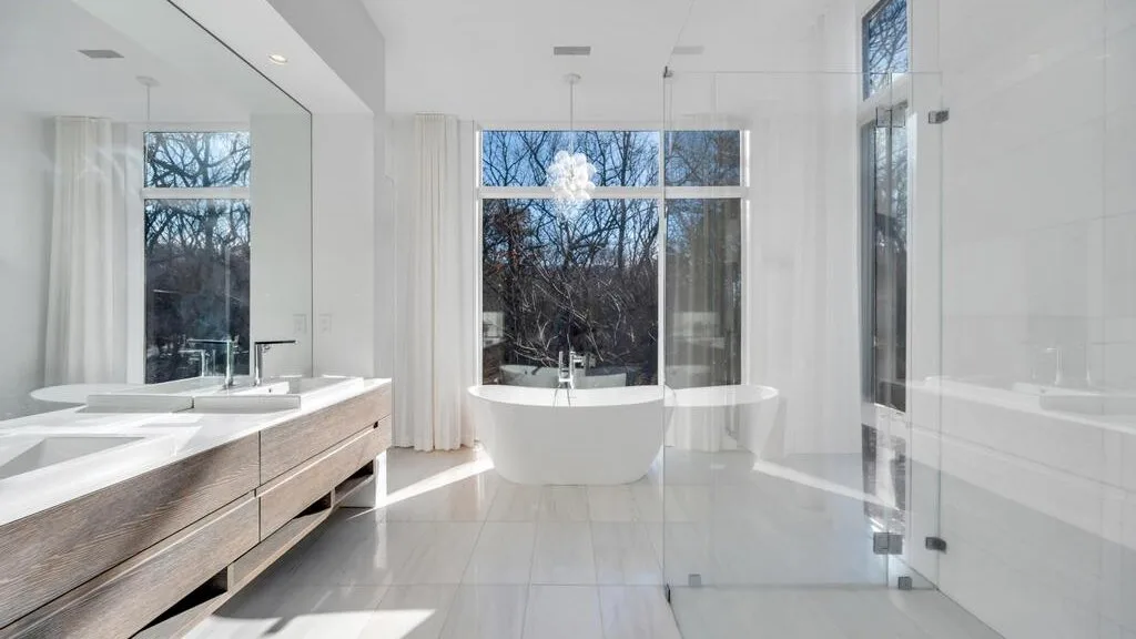 Un baño luminoso con una bañera exenta junto a grandes ventanas.