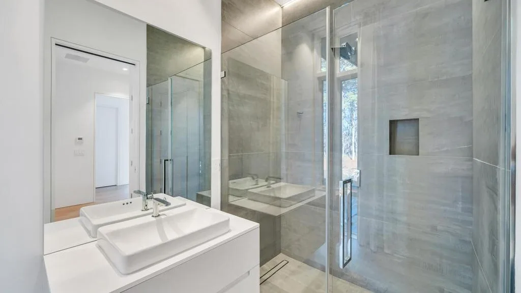 Un baño moderno con un amplio lavabo y una ducha con mampara de vidrio.