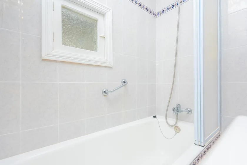 A tiled bathroom with a bathtub and shower fixtures.