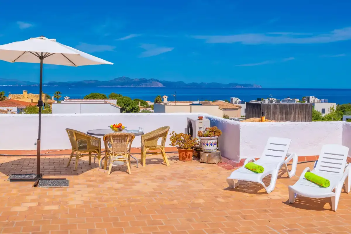 A rooftop terrace with outdoor seating and loungers overlooks the sea.