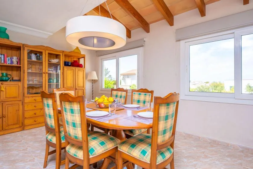 A dining room with a wooden table, patterned seating, and large windows.
