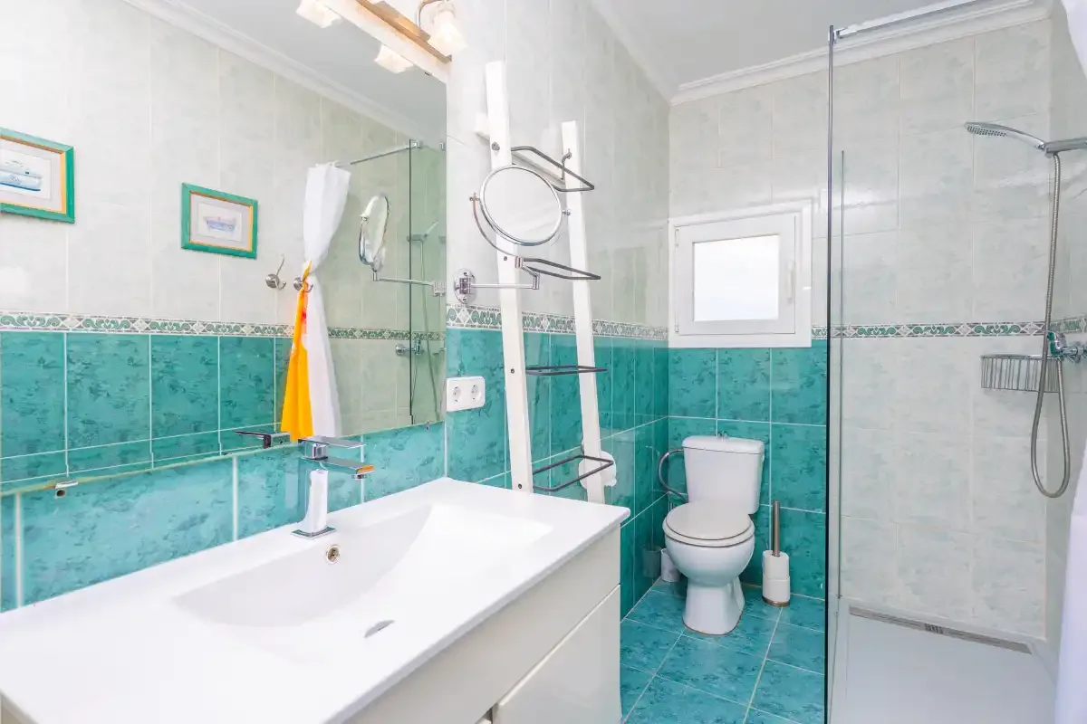 A bright bathroom with a sink, toilet, and glass shower.