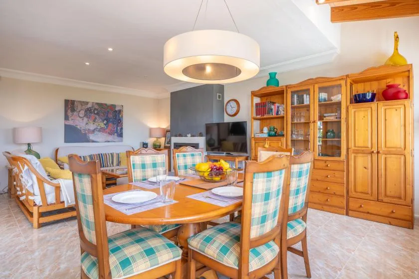A dining area with a wooden table and seating beside a living area.