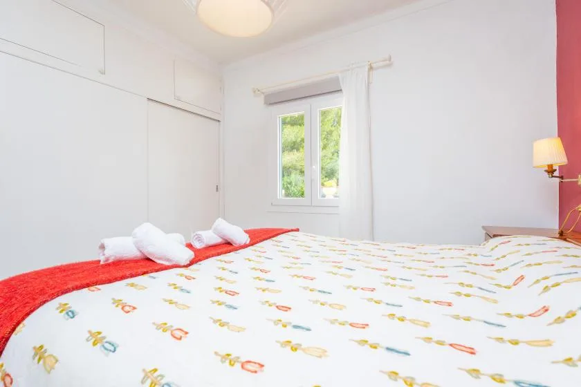 Bedroom with a patterned bedspread and a window overlooking greenery.