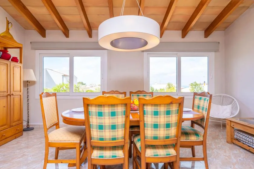 A dining area with a wooden table and chairs beneath exposed ceiling beams.