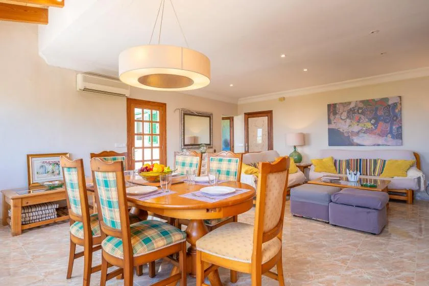 A bright dining and living area with a wooden table and colorful seating.