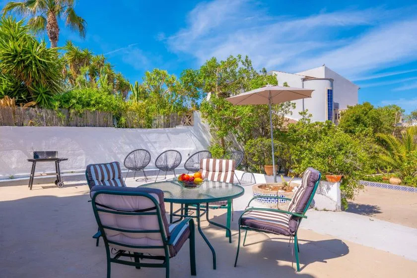 An outdoor patio with a table, seating, and an open umbrella.