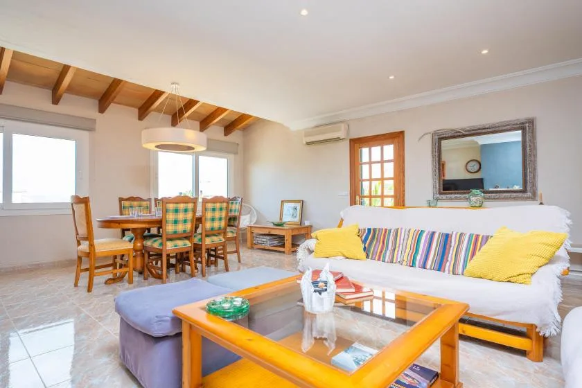 A bright living and dining area with a white sofa and wooden dining table.
