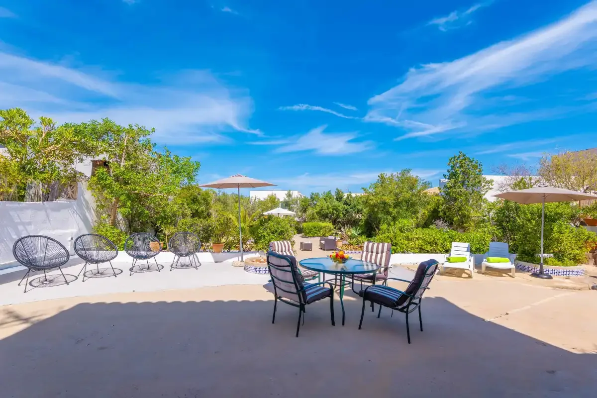 An outdoor patio with a dining table, seating, and surrounding greenery.