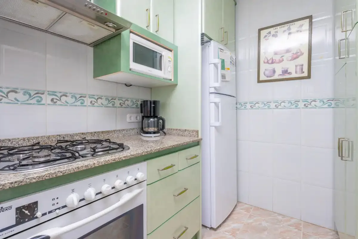 A tiled kitchen with a cooktop, oven, and refrigerator.
