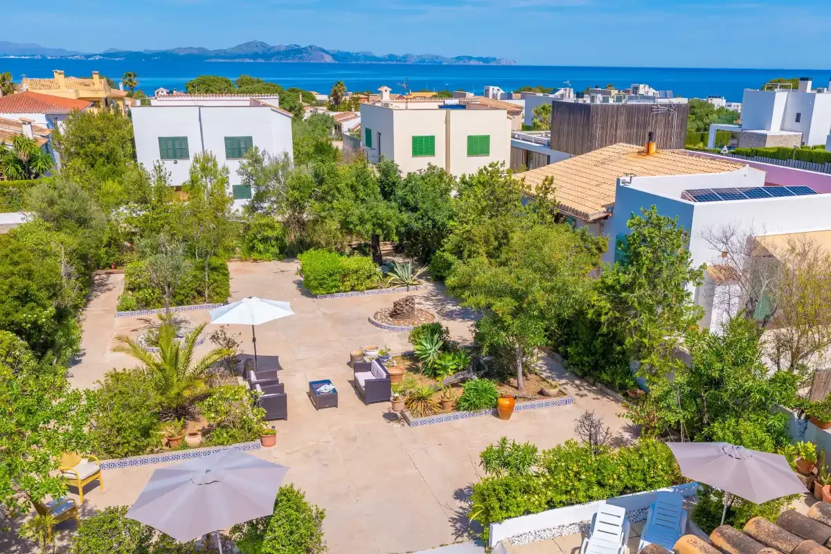 A landscaped courtyard with seating and shade umbrellas overlooks the sea.