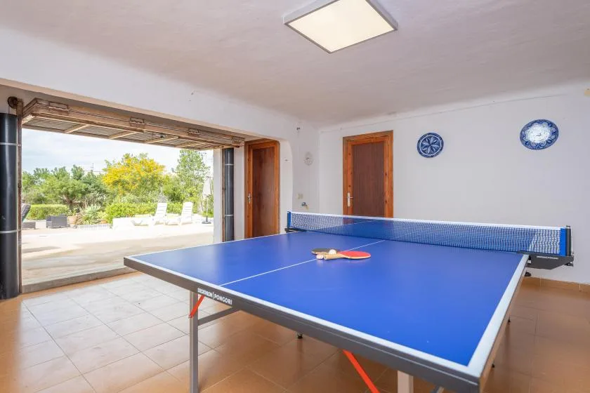 A game room with a blue ping-pong table beside open patio doors.
