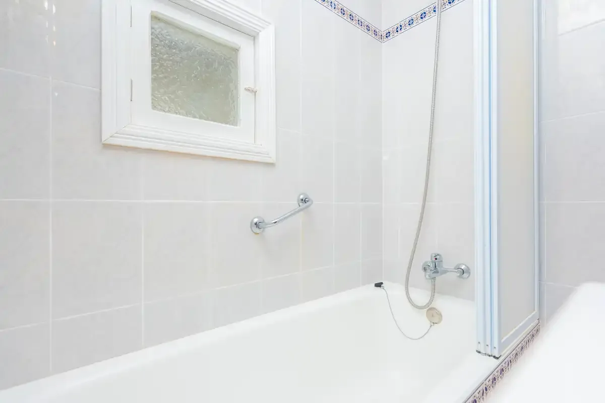 A tiled bathroom with a bathtub and handheld shower.