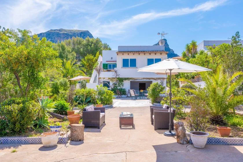 A garden patio with outdoor seating and a large shade umbrella.