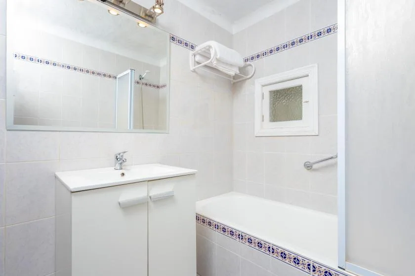 A tiled bathroom with a sink, mirror, and bathtub.