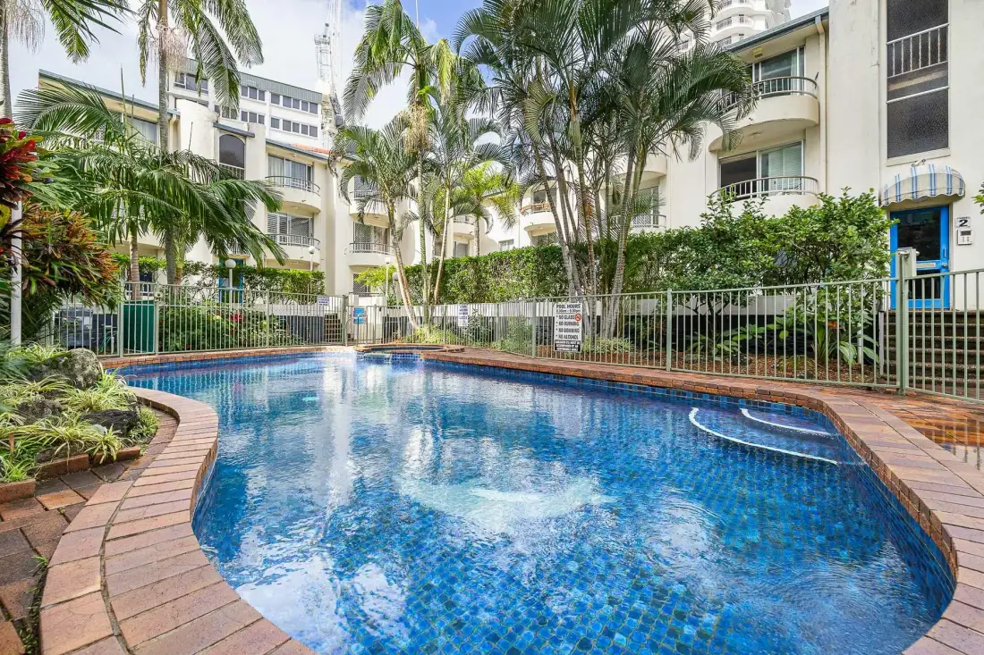 Una piscina rodeada de palmeras y edificios de apartamentos.