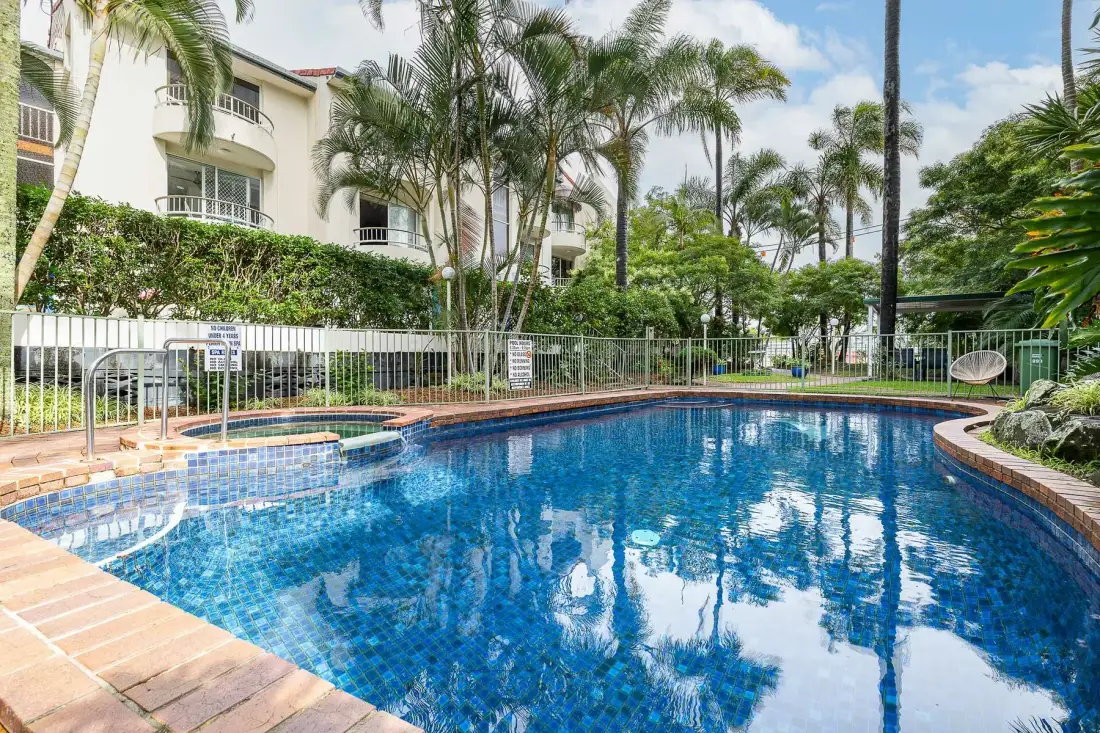 Una piscina rodeada de plantas tropicales y palmeras.