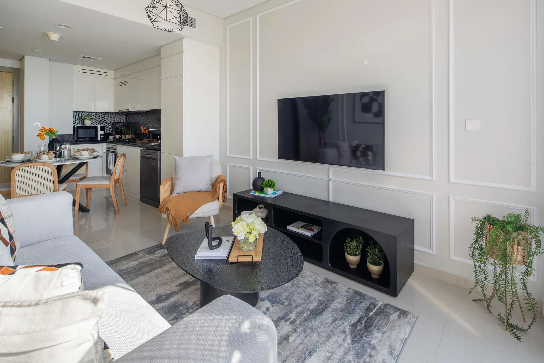 Sala de estar con televisor montado en la pared y cocina-comedor abierta.