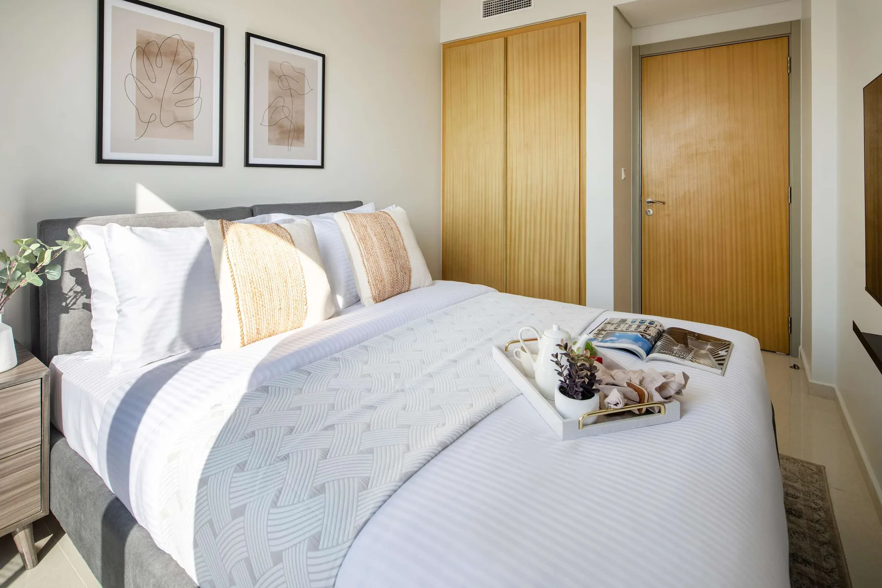 Un dormitorio con una cama bien tendida y cuadros enmarcados sobre el cabecero.